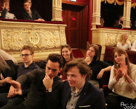 Na zdjęciu fragment widowni Teatru. Na fotelach grupa młodych osób około 17 lat. Uśmiechają się. Część z nich klaszcze i patrzy na widownię. W tle fragment loży parterowej złoto zdobionej.