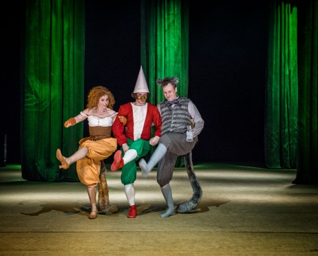 Na scenie trzy osoby, w tle pasma zielonych kotar. Kobieta i dwóch mężczyzn trzymają się pod ręce, tańczą unosząc nogi w górę. Kobieta ubrana na rudo, z rudymi kręconymi włosami, z dużym dekoltem. W środku mężczyzna przebrany za pinokia - ma czerwony surdut, czerwone buty, zielone bufiaste spodnie i szpiczastą białą czapkę w kształcie tutki na głowie. Z prawej strony drugi mężczyzna cały na szaro, w szarej kamizelce przypominającej futro. Ma przyczepione na głowie uszy a na plecach długi koci ogon.