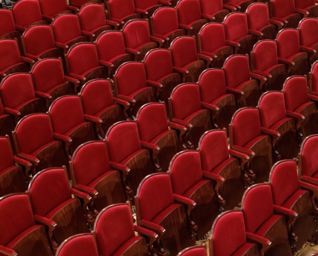Zdjęcie zrobione z góry na fotele na widowni Teatru Słowackiego. Rzędy krzeseł, obitych na bordowo, z uniesionymi siedziskami. Widownia jest pusta.