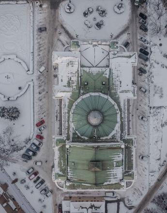 Zima, ujęcie z góry na Teatr im. J. Słowackiego. Teren wokół przykryty śniegiem. Widok na zielony dach z kopułą, wokół parkingi z autami, ulice, alejki i drzewa.