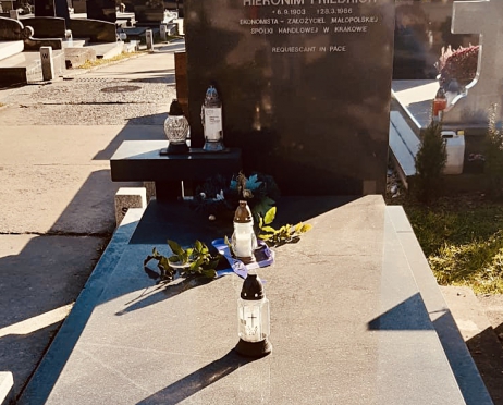 Zdjęcie grobu Zofii Jaroszewskiej na cmentarzu. Nagrobek jest kamienny. W tle inne groby i tuje. Na płycie nagrobka stoją znicze.