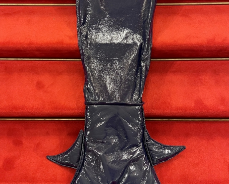 Na schodach przykrytych czerwonym dywanem leży kostium - czarny ogon syreny czyli płetwa z poczwórnym zakończeniem. Materiał jest czarny, z połyskiem.
