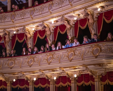 Na zdjęciu loże pierwszego i drugiego piętra. Zdjęcie zrobione z dołu. W lożach siedzą młodzi ludzie. Patrzą w kierunku widowni.